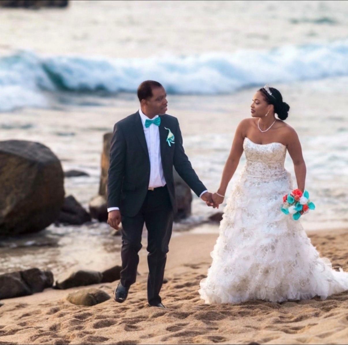Bride and groom walking hand in hand along the beach