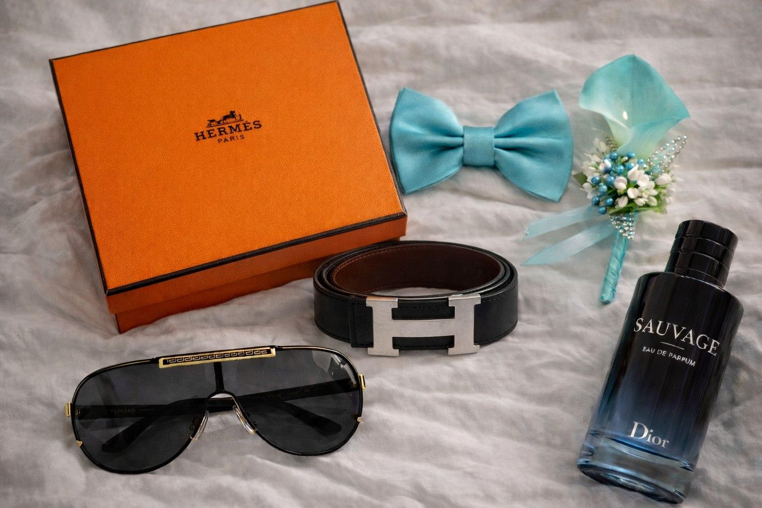 Groom's accessories flat lay with cologne, sunglasses, and boutonniere