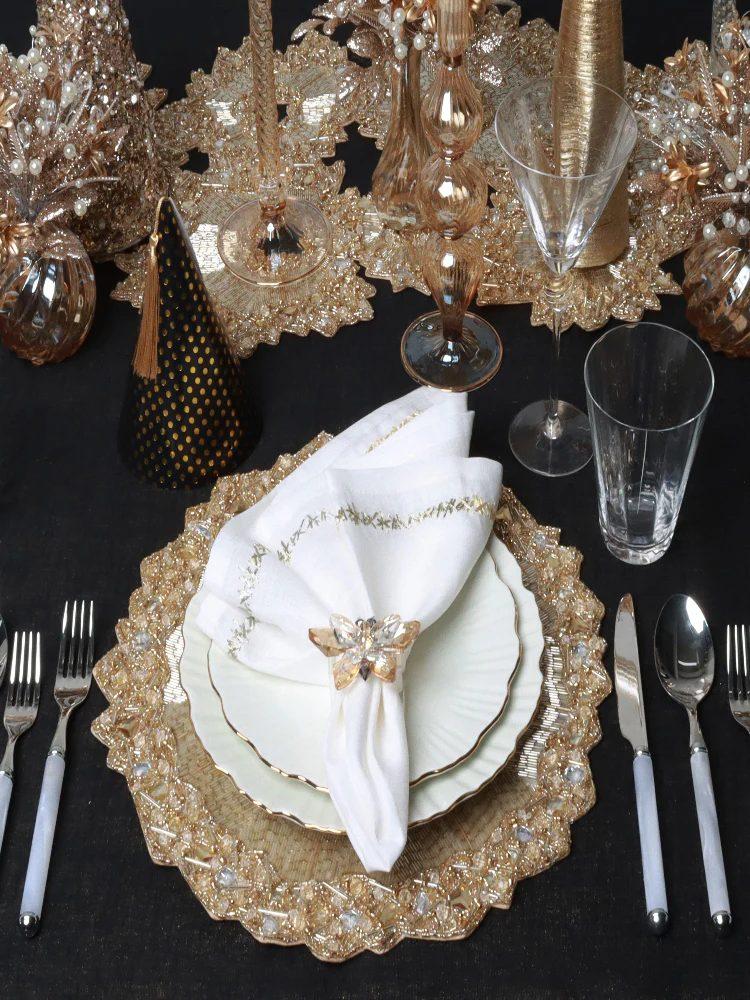 White and gold place setting with beaded charger, pleated napkin, and printed menu