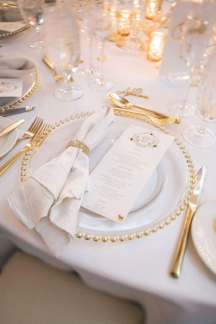 Candlelit ivory and gold tablescape with greenery garland, roses, and champagne