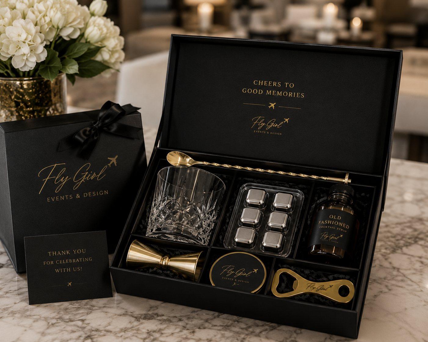 Black and gold Fly Girl cocktail gift box with crystal glass, gold barware, and old fashioned syrup